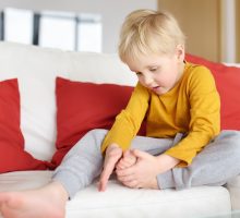 Little boy examines a splinter in his foot