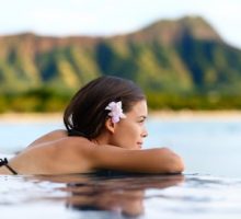 Infinity pool resort woman relaxing at sunset overlooking Waikiki beach
