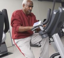 senior man exercising on stationary bike in health club for his workout