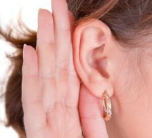 woman cupping her ear to listen better because she is hard of hearing
