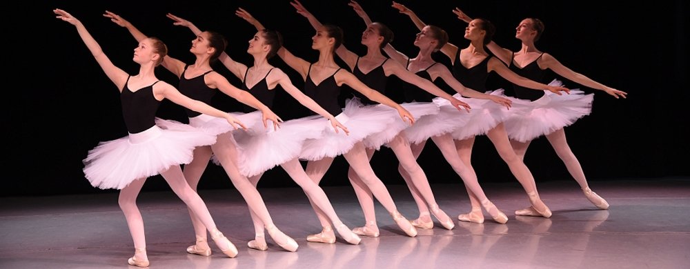 Ballerinas in a row with arm outstretched and foot pointed.
