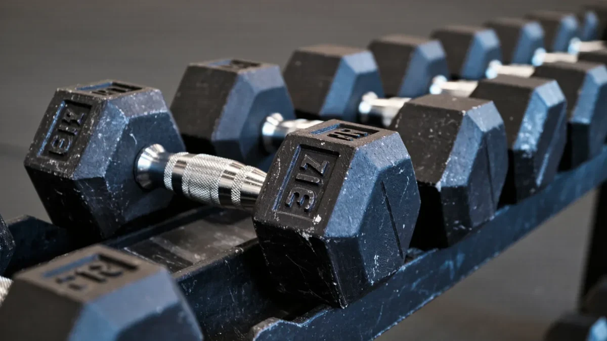 Close-up of well-used iron dumbbells stacked on a rack