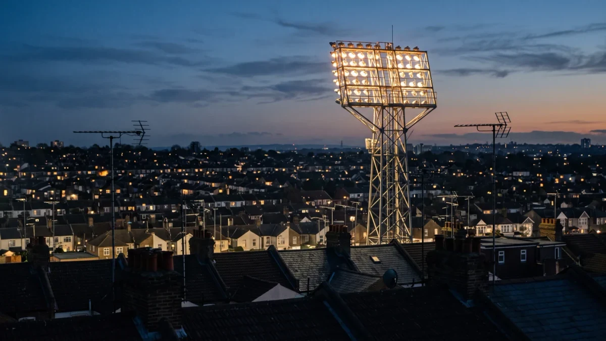 Stadium floodlights above darkened suburban rooftops
