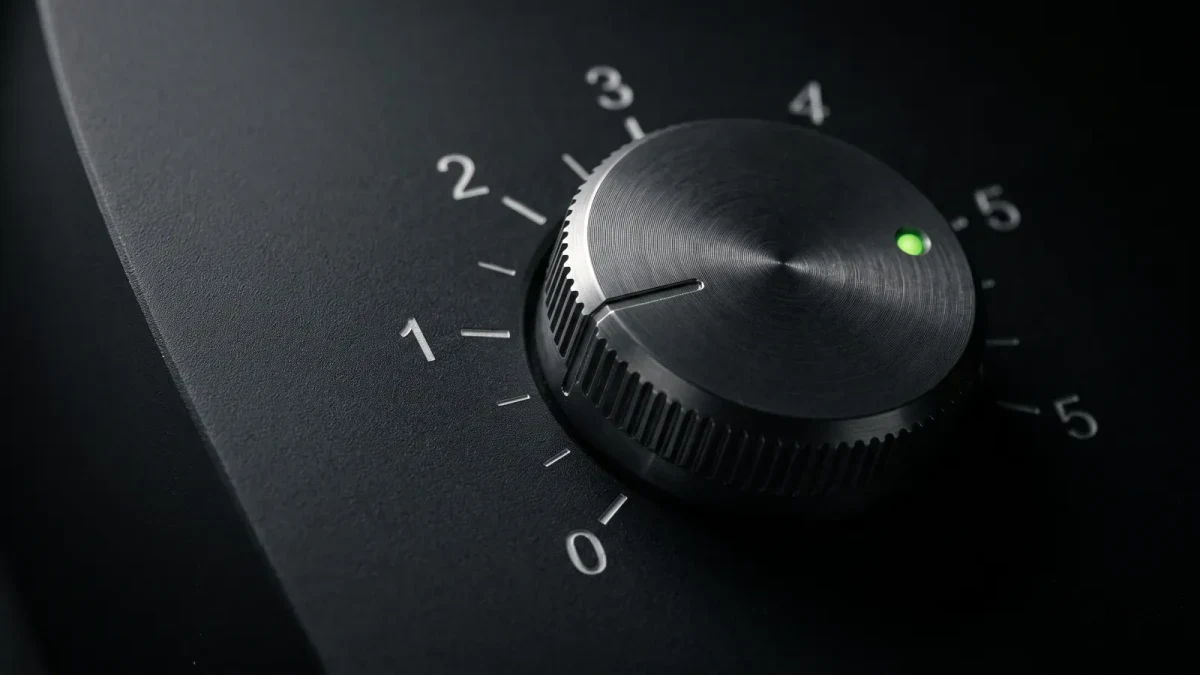 Macro of a metal control dial set low on a dark panel