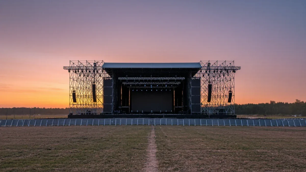 Empty festival main stage scaffold at dusk under haze
