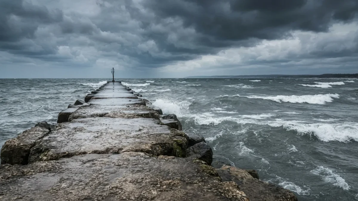 Whitecapped lake water under gathering storm clouds beside an empty breakwater