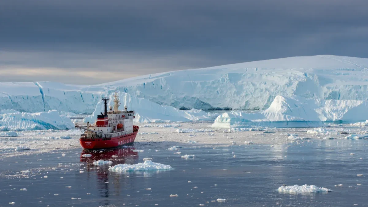 Research vessel at the edge of sea ice near icebergs
