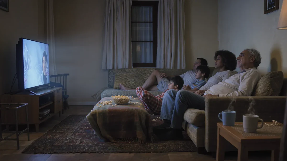 A family watching a newly released film on a living room television
