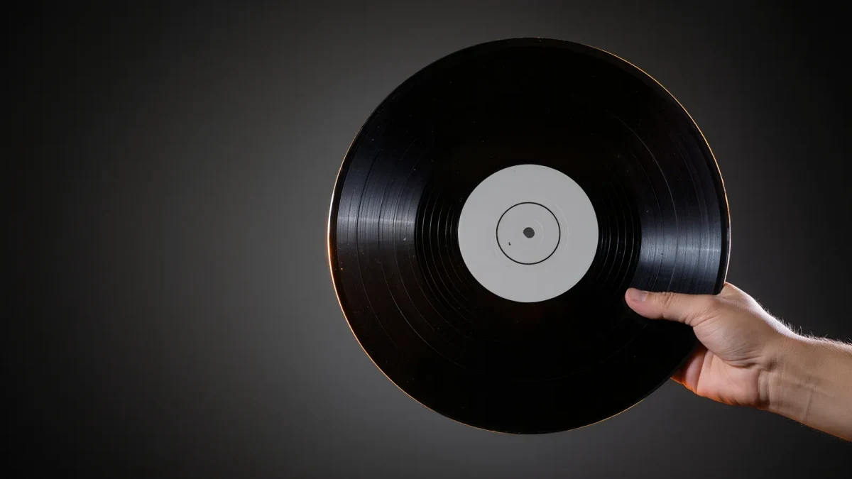 Freshly pressed black vinyl LP held toward studio light