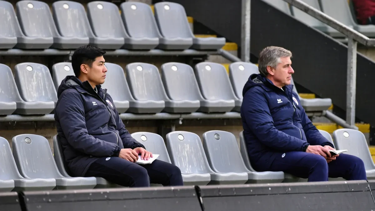 Scouts watching a match from a windswept stand