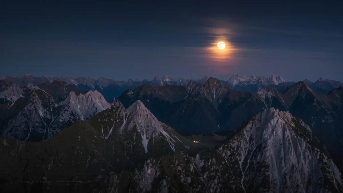 Night skyline of mountain ridges under a bright full moon