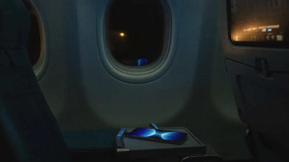 Dim airplane cabin at night with a glowing phone on a tray table