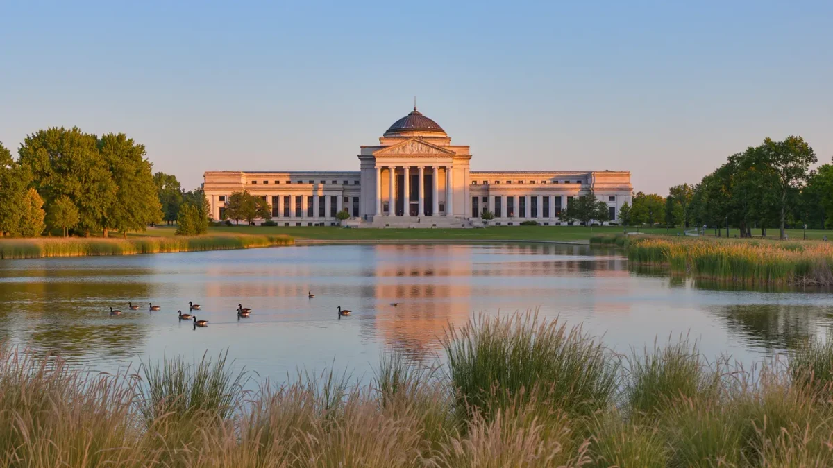 Museum of Science and Industry building beside Jackson Park lagoon at dusk
