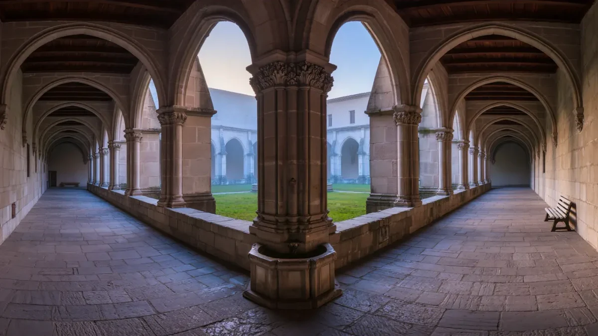 Monastery cloister arcade around misted grass garth at dawn
