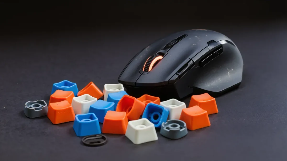 Studio close-up of a worn gaming mouse beside team-colored keycaps