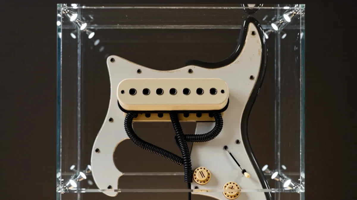 Close-up of a vintage-style single-coil pickup mounted on display in a museum case