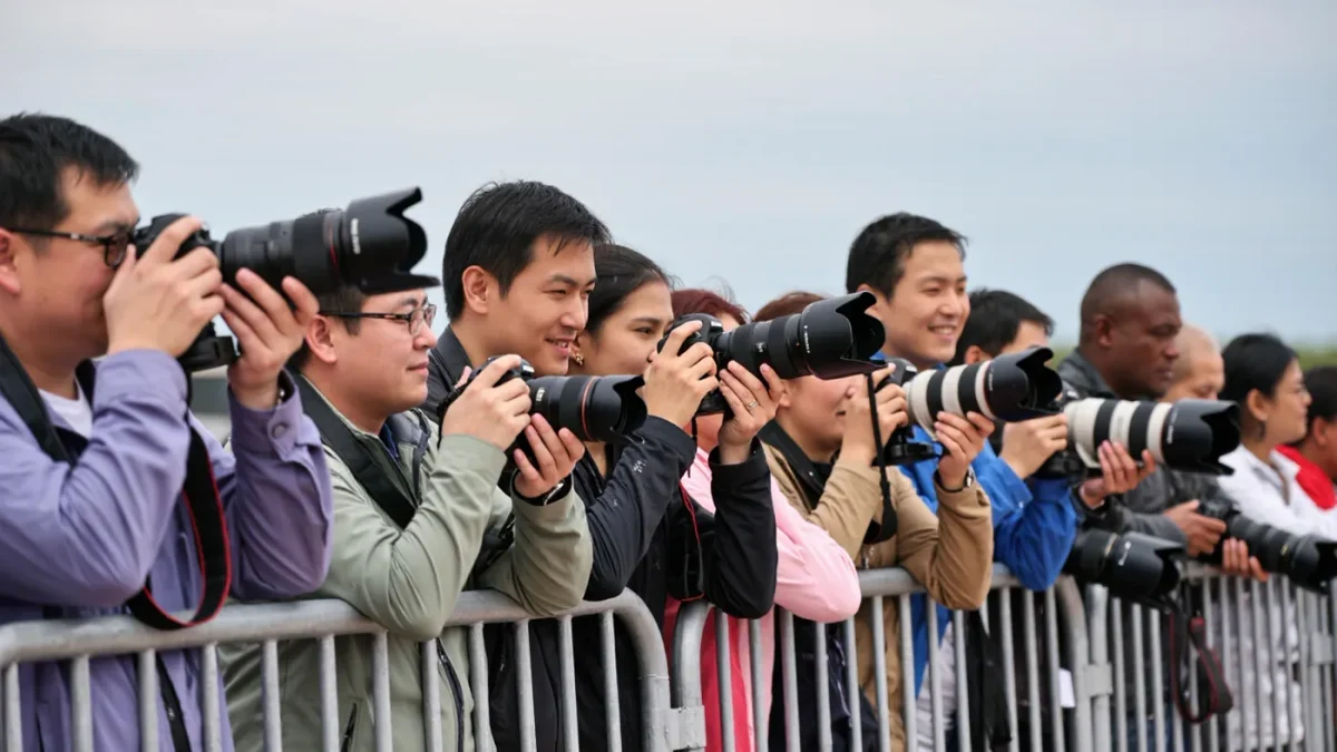 Photographers' cameras raised at a barricaded event line