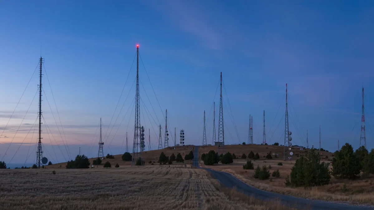 Transmission towers of multiple stations silhouetted at dusk