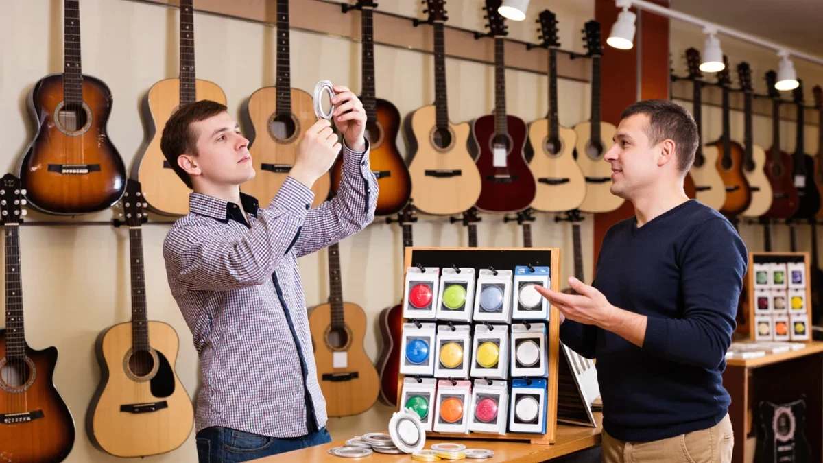 Two guitarists comparing wound bass strings in a music shop