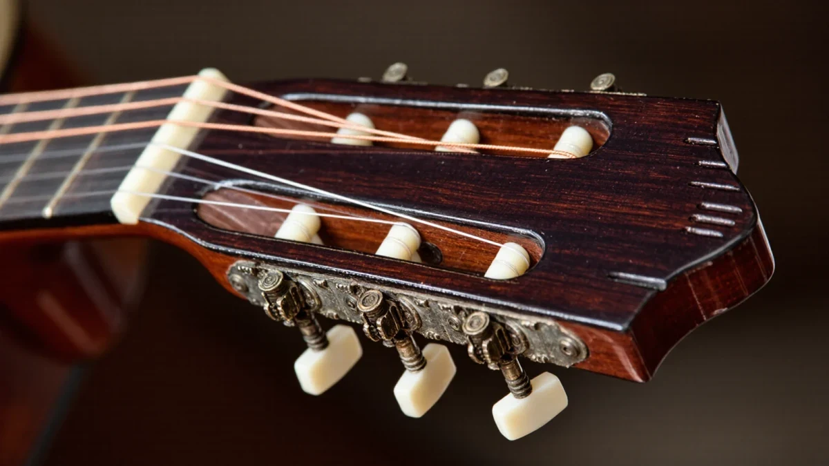 Close-up of nylon strings crossing the slotted headstock of a classical guitar