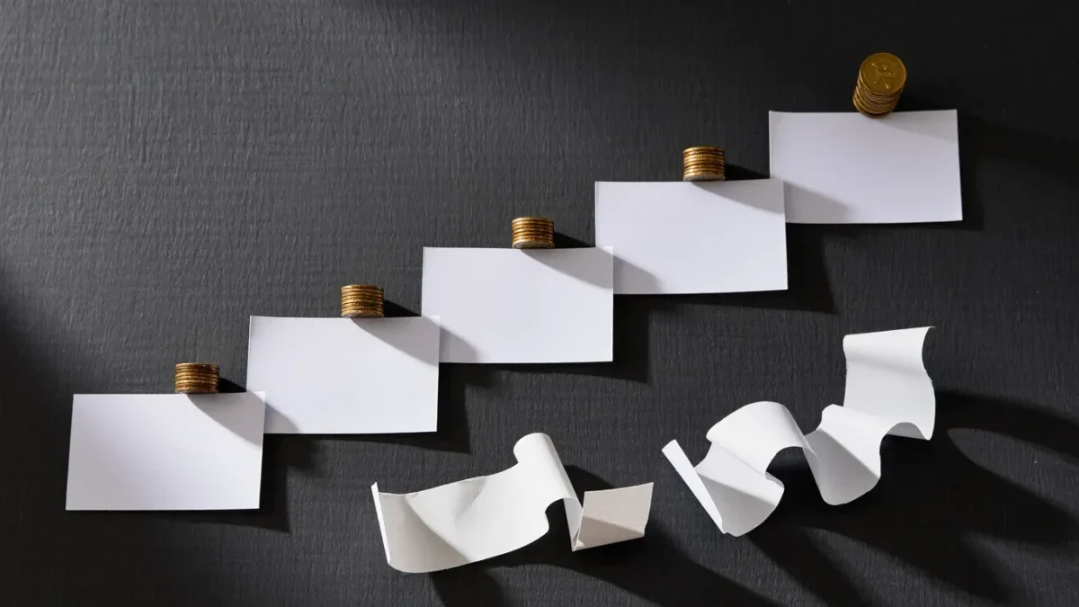 Rising paper price chart with coins and receipts on dark surface