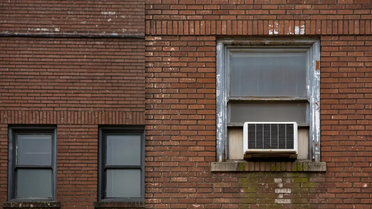 Older garden-style apartment blocks photographed from an adjacent parking area