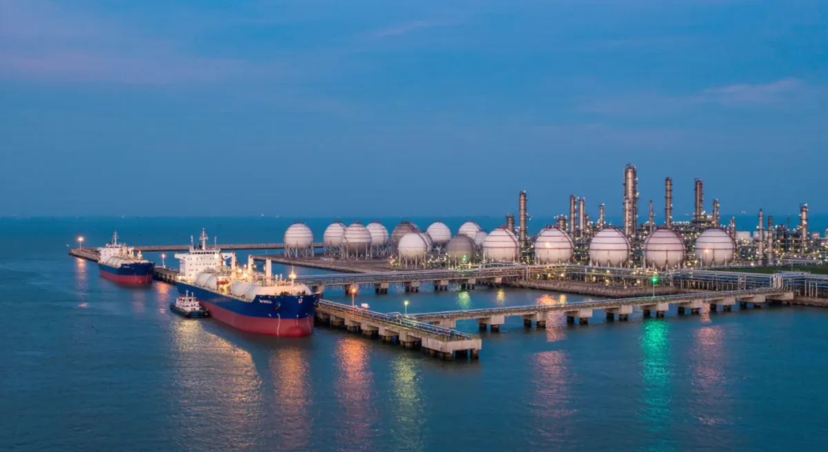LNG tankers and liquefaction towers at a Gulf gas export terminal at dusk