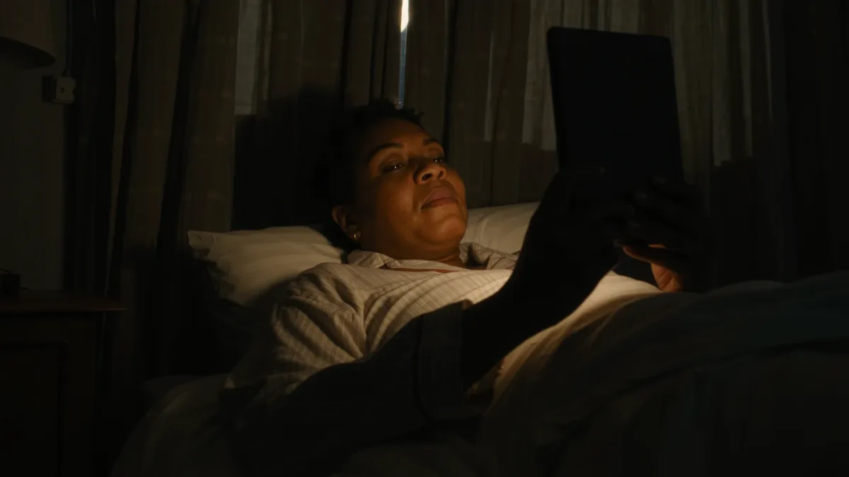 Woman reading an unbranded e-reader with amber warm light in bed