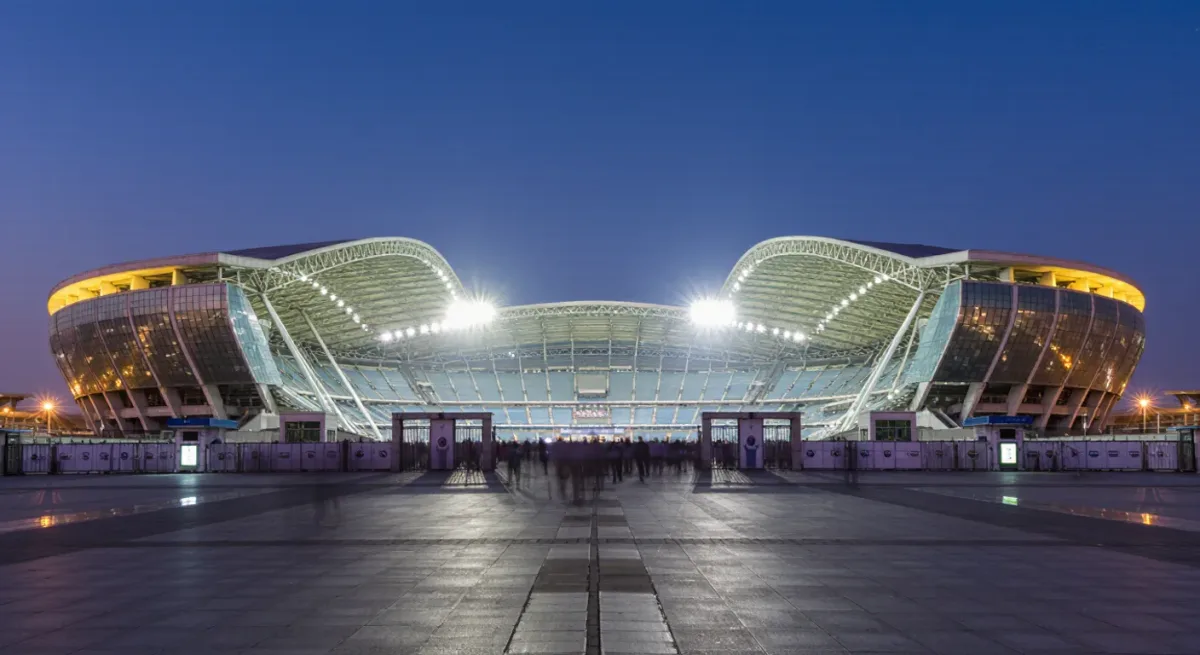 Wide evening view of a floodlit football stadium from outside