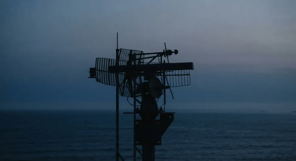 Silhouetted abstract antenna array against deep blue dusk sky over sea