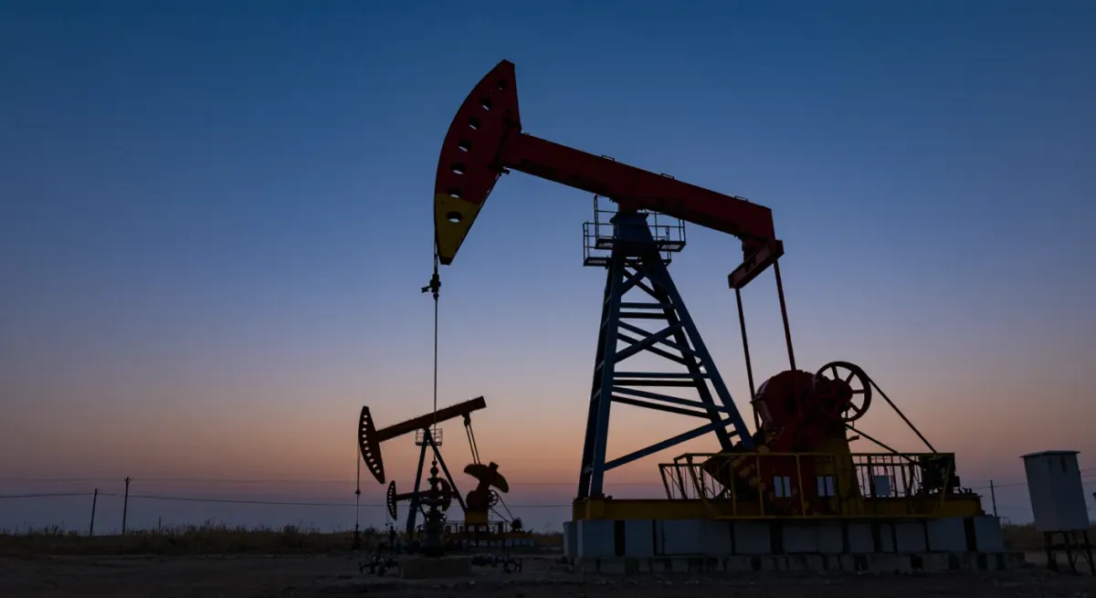 Oil pump jacks at dusk in a Gulf desert field