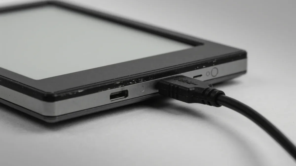 Close-up of a weathered unbranded e-reader with its USB port and cable