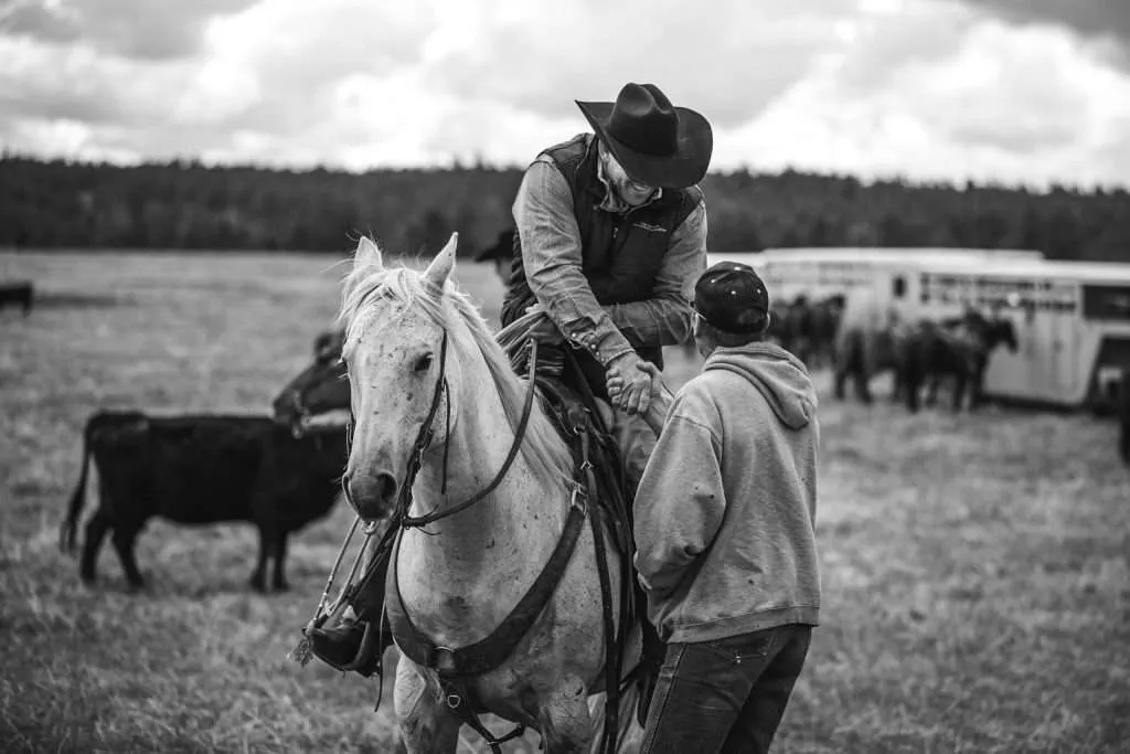 Western Ranch Brokers Bill Boyce shaking hands while on a horse