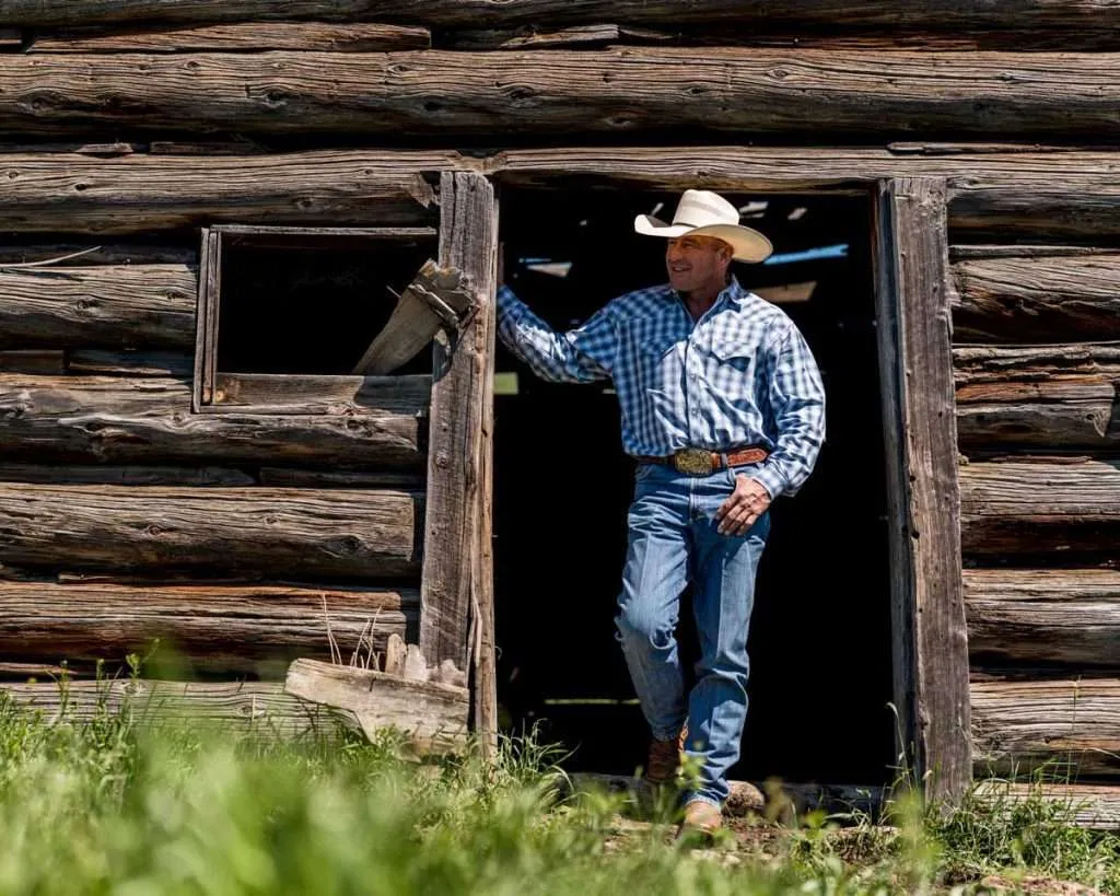 Ranch broker Bill Boyce in front of a log cabin