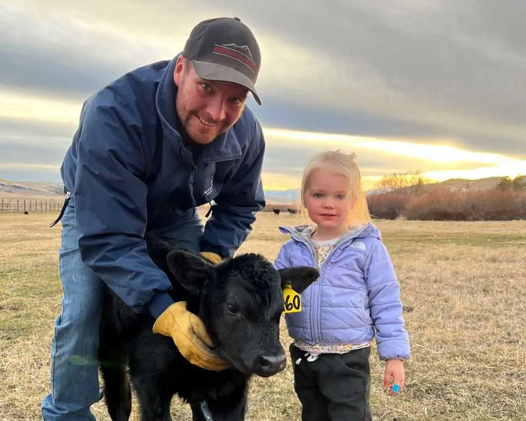 Ranch broker Caleb Campbell with daughter and a calf