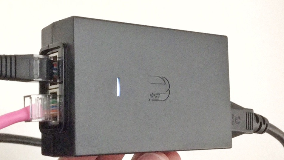 Ubiquiti PoE injector with Ethernet cables in its LAN and PoE ports and its status light on
