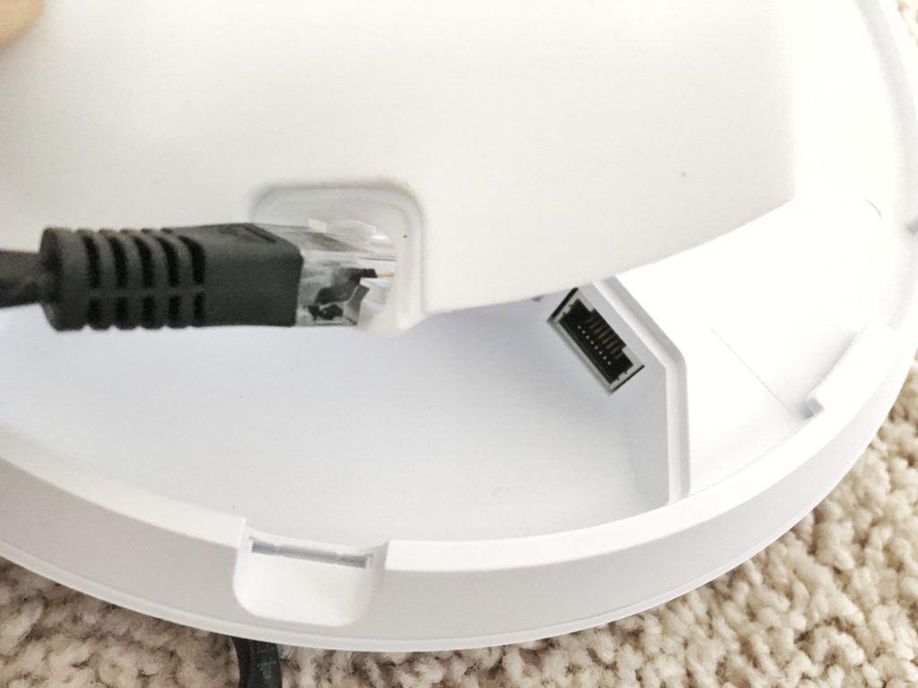 RJ45 connector being passed through the hole in the UniFi access point's rubber port cover