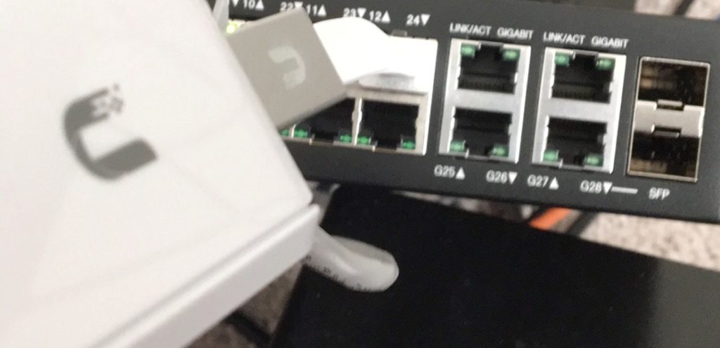 Close-up of the UniFi Cloud Key's Ethernet cable plugged into a network switch beside its gigabit and SFP ports