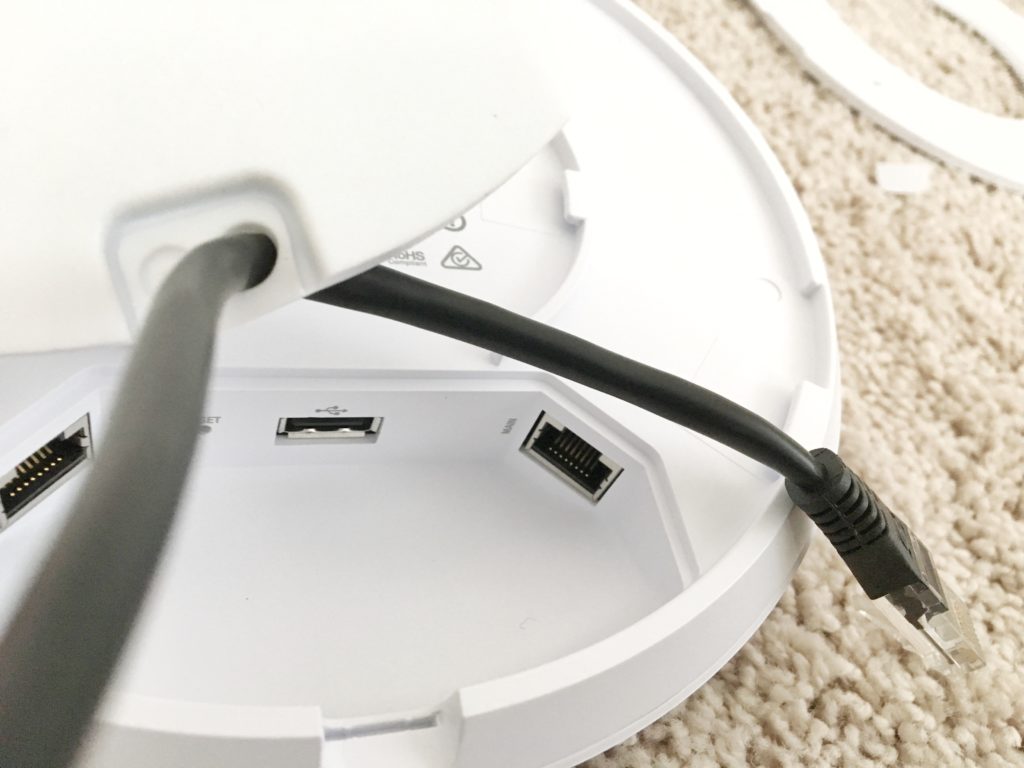 Ethernet cable threaded through the UniFi port cover before being plugged into the main port