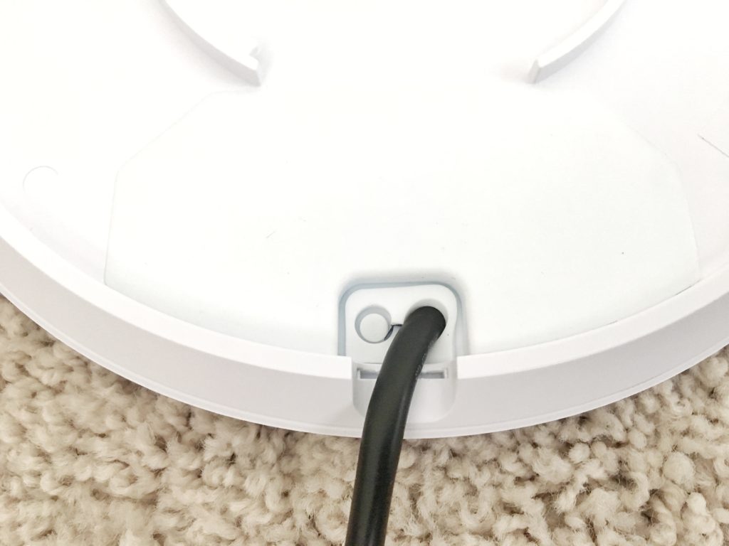 UniFi access point with the port cover closed and the Ethernet cable exiting through its sealed opening