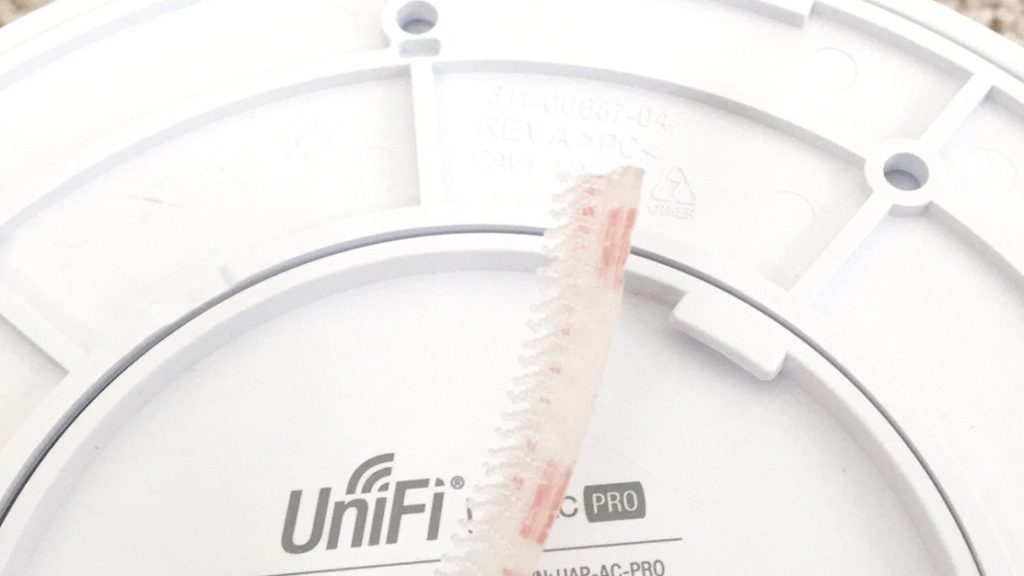 Strip of 3M Dual Lock fastener held against the back of a UniFi AP AC Pro mounting plate