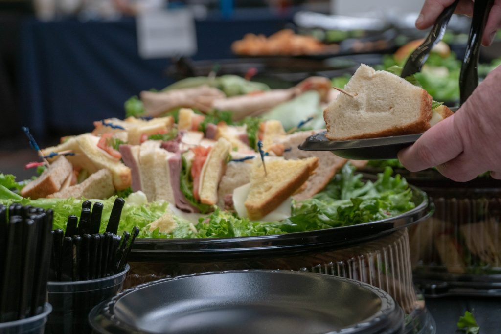 Guest serving a deli sandwich from a catered sandwich platter at the summit lunch