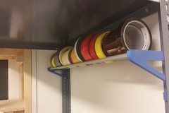 Tape roll holder for storage rack/cabinet
